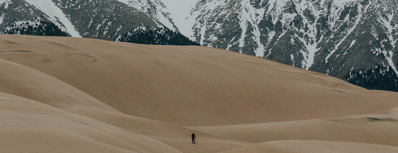 randonneur dans un immense paysage de sable et de roche enneigé